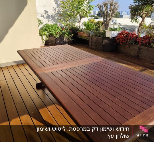 שולחן עץ על דק עם עציצים מסביב